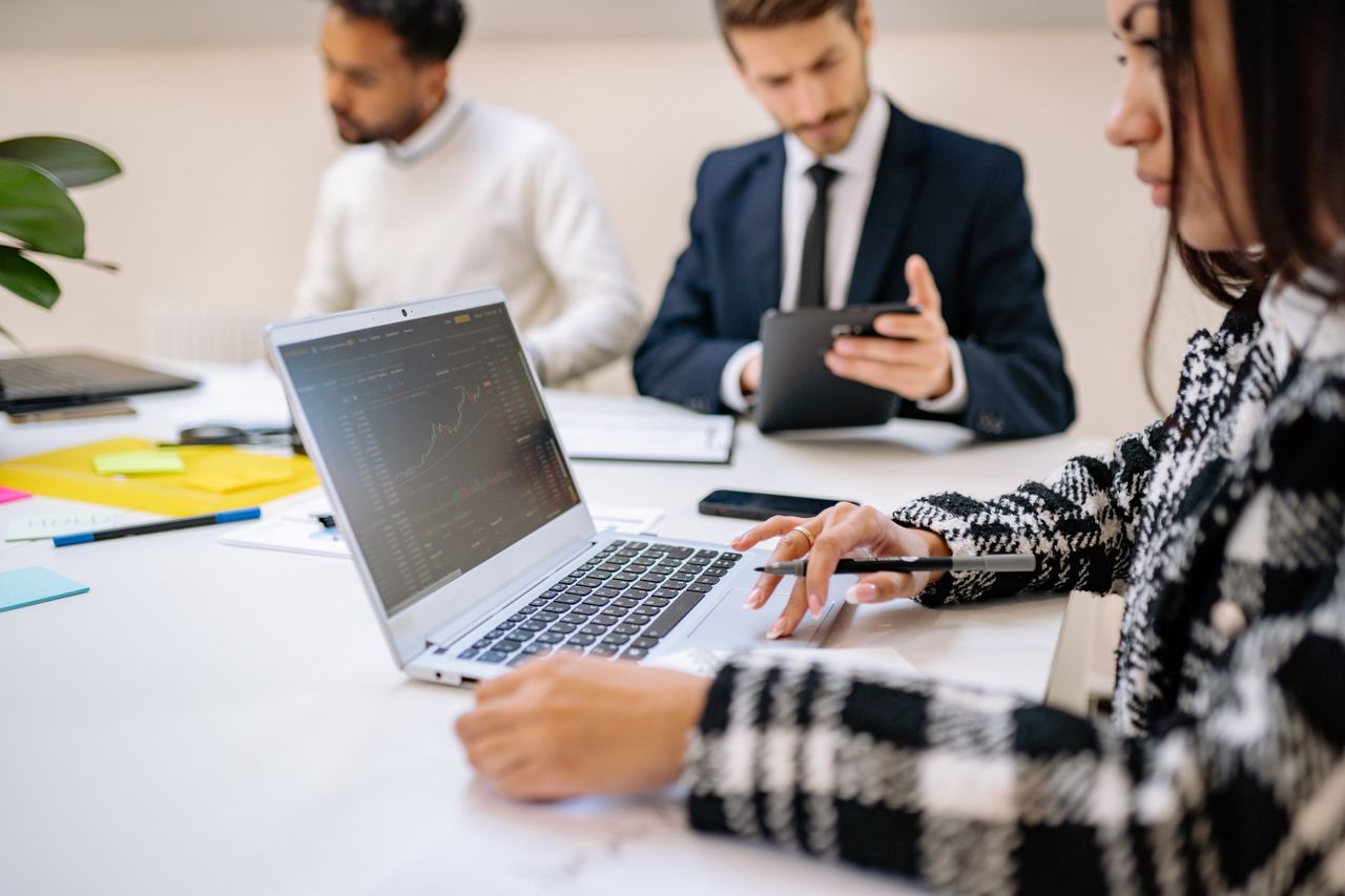 Mastering the First Impression: Your intriguing post title goes here Professional team working on stock market analysis with laptops and tablets in modern office setting.